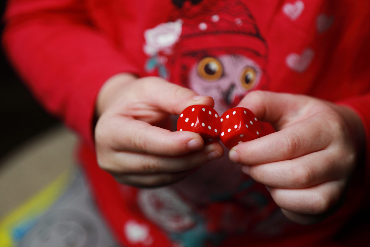 Close up of child's hands holding two red dice.